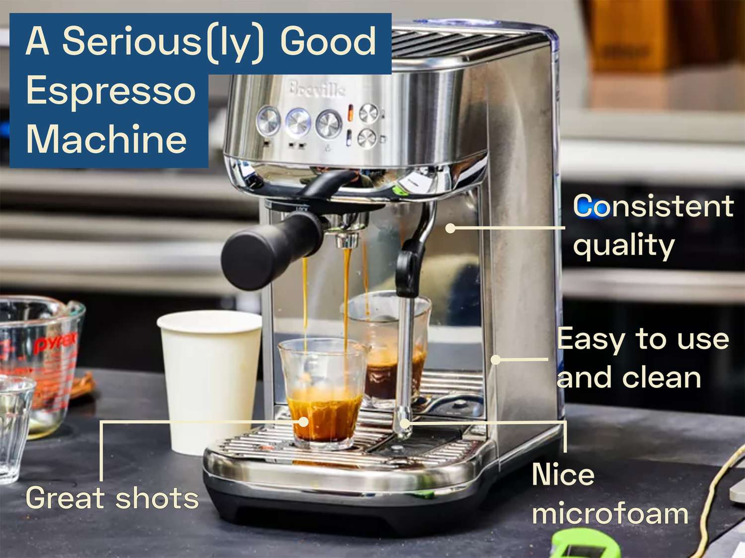An espresso machine on a kitchen countertop brewing a shot of espresso into a small glass.
