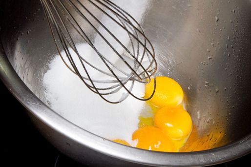 Eggs yolks, granulated sugar, and whisk in a metal bowl.