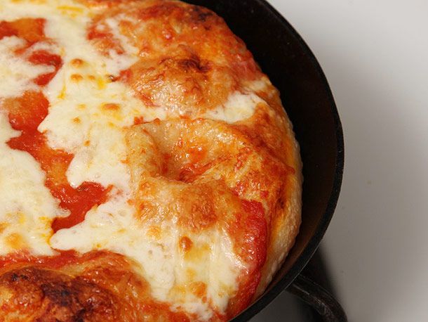 Pizza baked in cast iron pan with tomato sauce and white cheese.