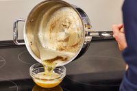 A person pours melted butter from the All-Clad Copper Core 10-Piece Cookware Set pan into a bowl