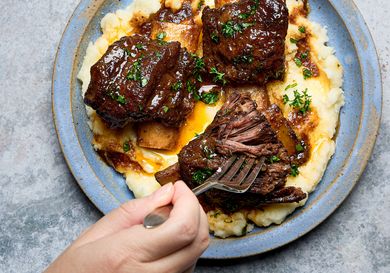 Short ribs served over mashed potatoes with a fork taking a piece