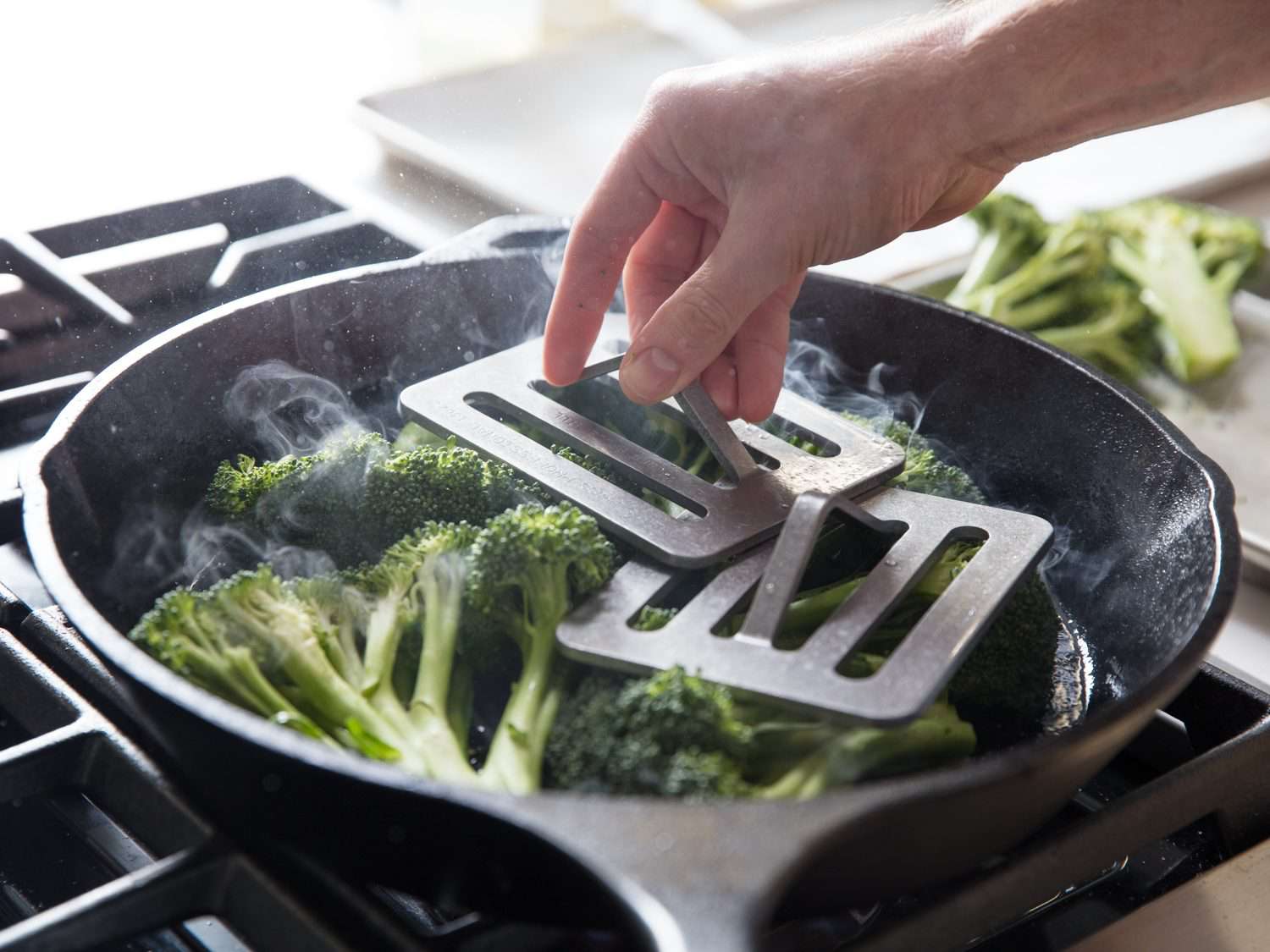 Using a Chef's Press for cooking broccoli in a cast iron skillet.