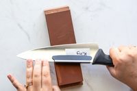 A person sharpening a knife on the King Whetstone