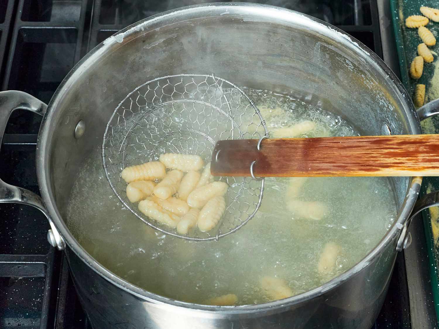 Overhead view of gnocchi being scooped out of boiling water