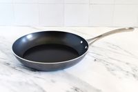 A Kyocera nonstick ceramic frying pan with a handle placed on a marble countertop