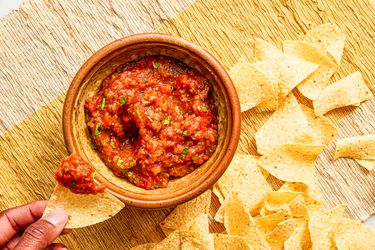 Overhead view of a hand dipping a chip in salsa 