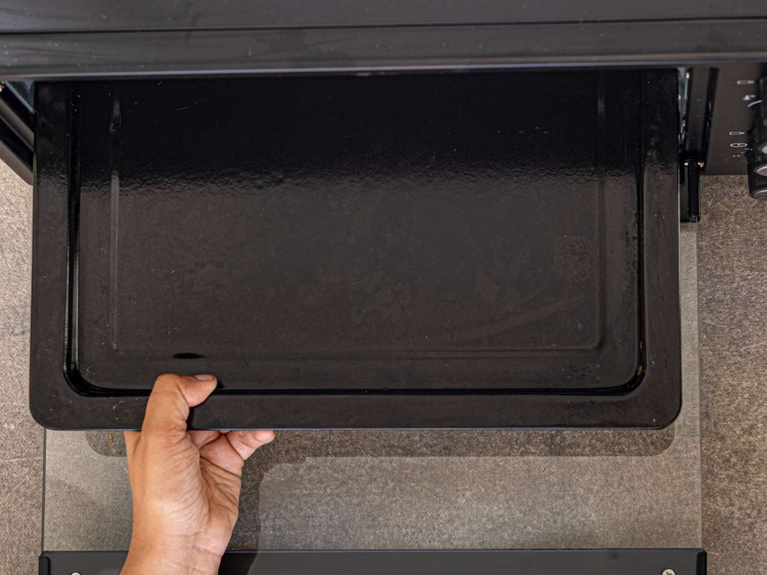 A hand pulling out the tray of an oven