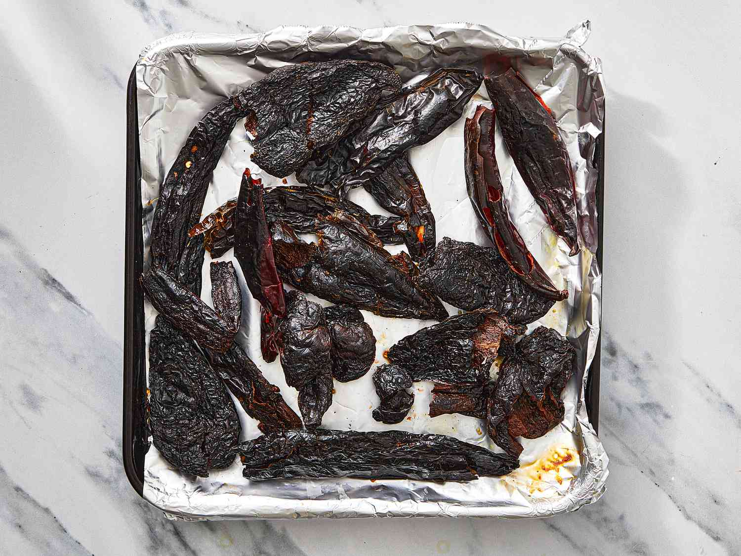 Charred dried chilies on a foil-lined baking sheet