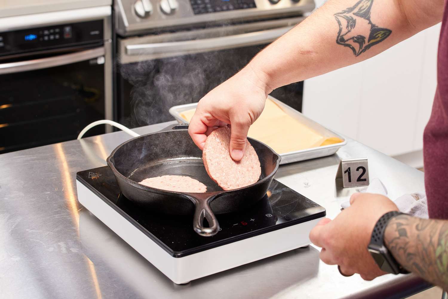 Meat being seared in a cast iron pan on the IKEA TILLREDA induction cooktop.