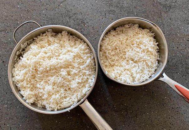 Two pots filled with cooked rice one large and one smaller placed on a dark surface