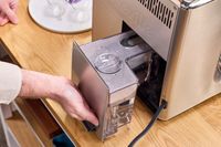 A person removes the water tank from the Breville The Oracle Dual Boiler Espresso Machine