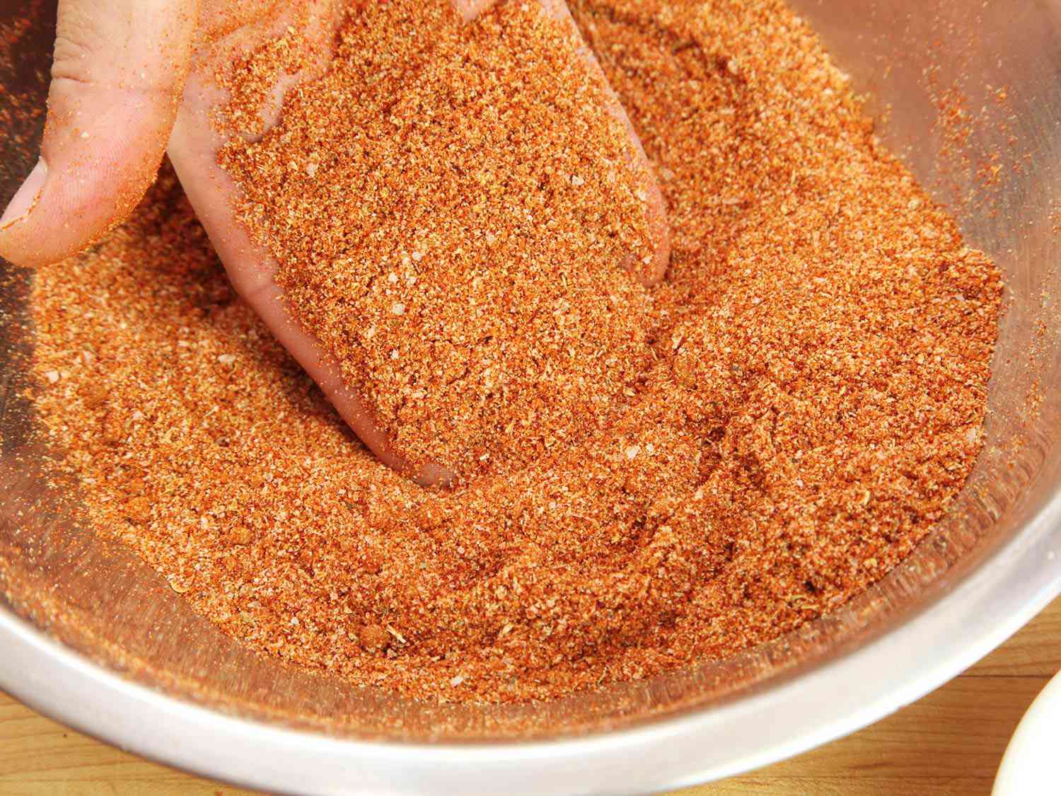 Closeup of barbecue rub in a mixing bowl. The author's hand has scooped some up to show to the camera.