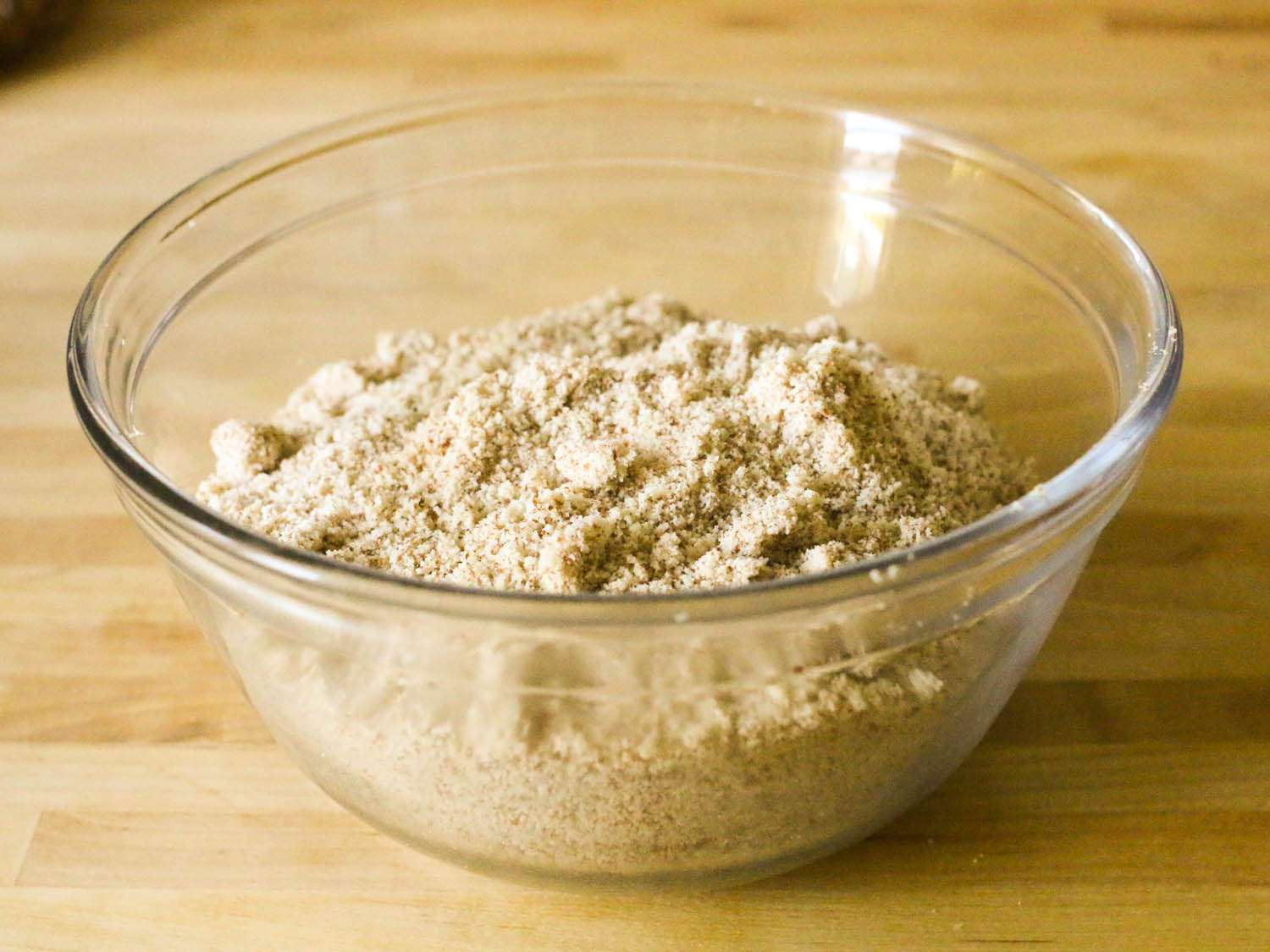 A glass bowl holding ground almond flour.
