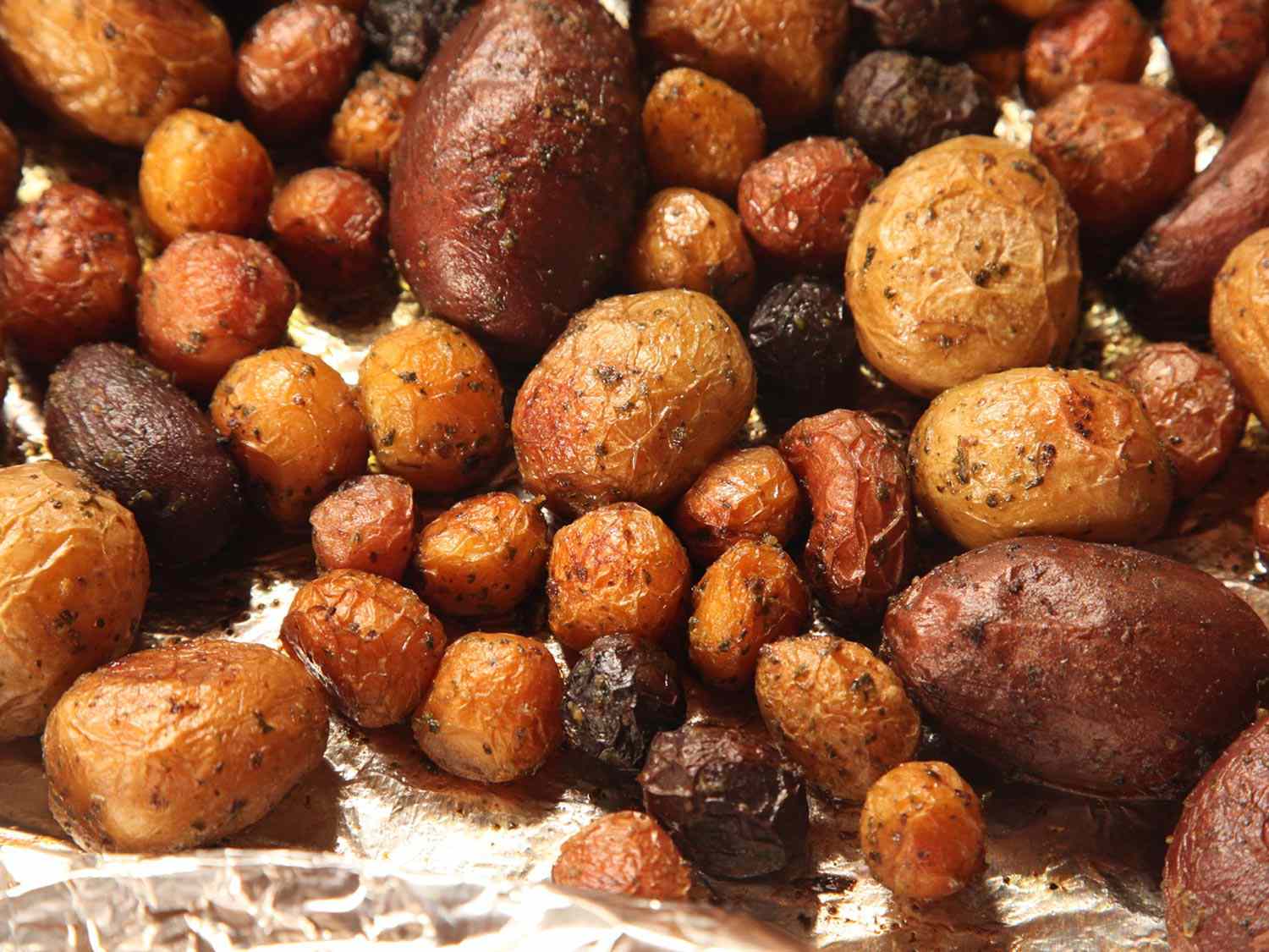 A sheet pan holding a variety of roasted potatoes of various sizes.