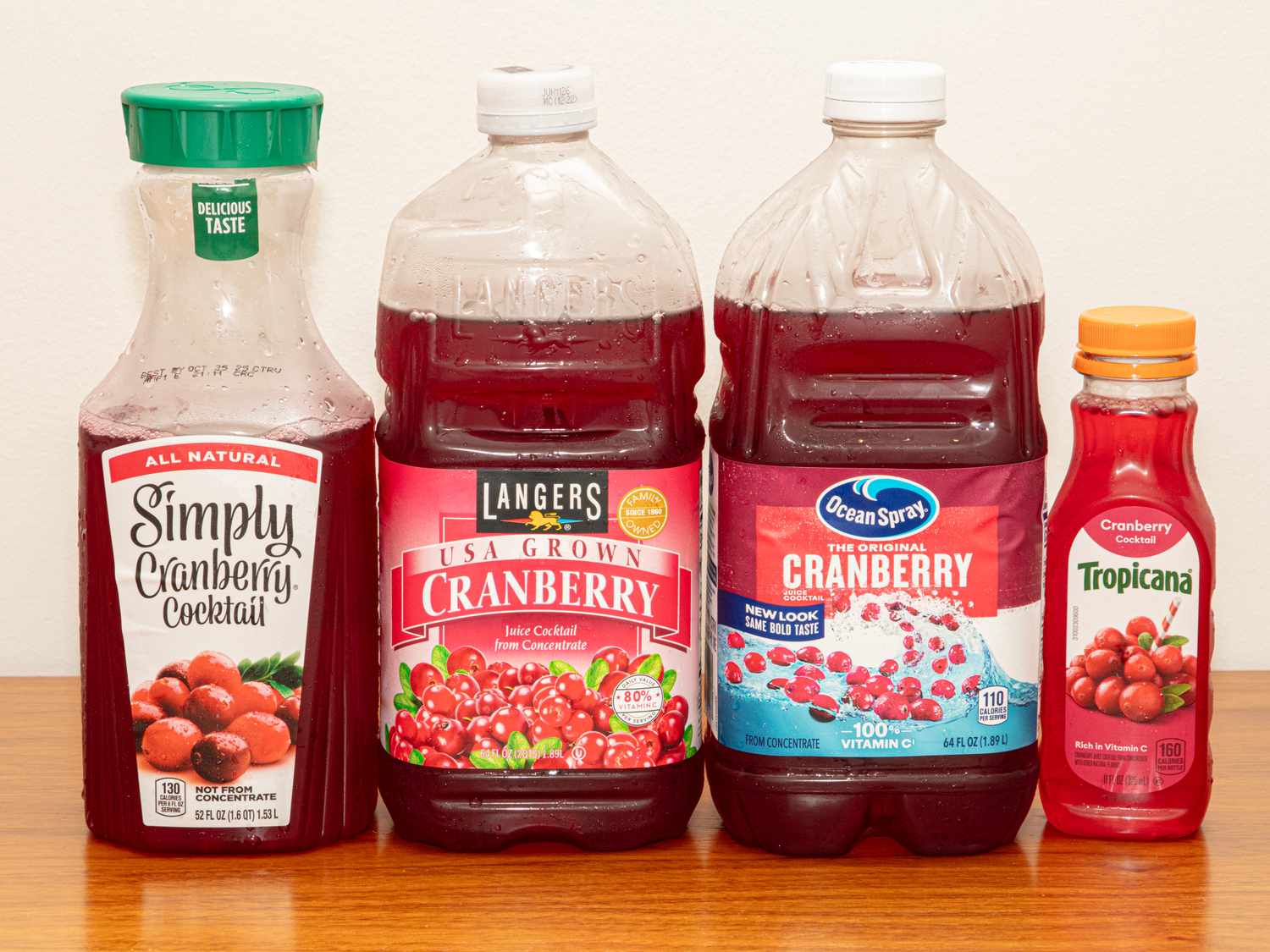 Four cranberry juice bottles from different brands displayed side by side on a table