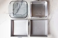 Four baking pans on a marble countertop.