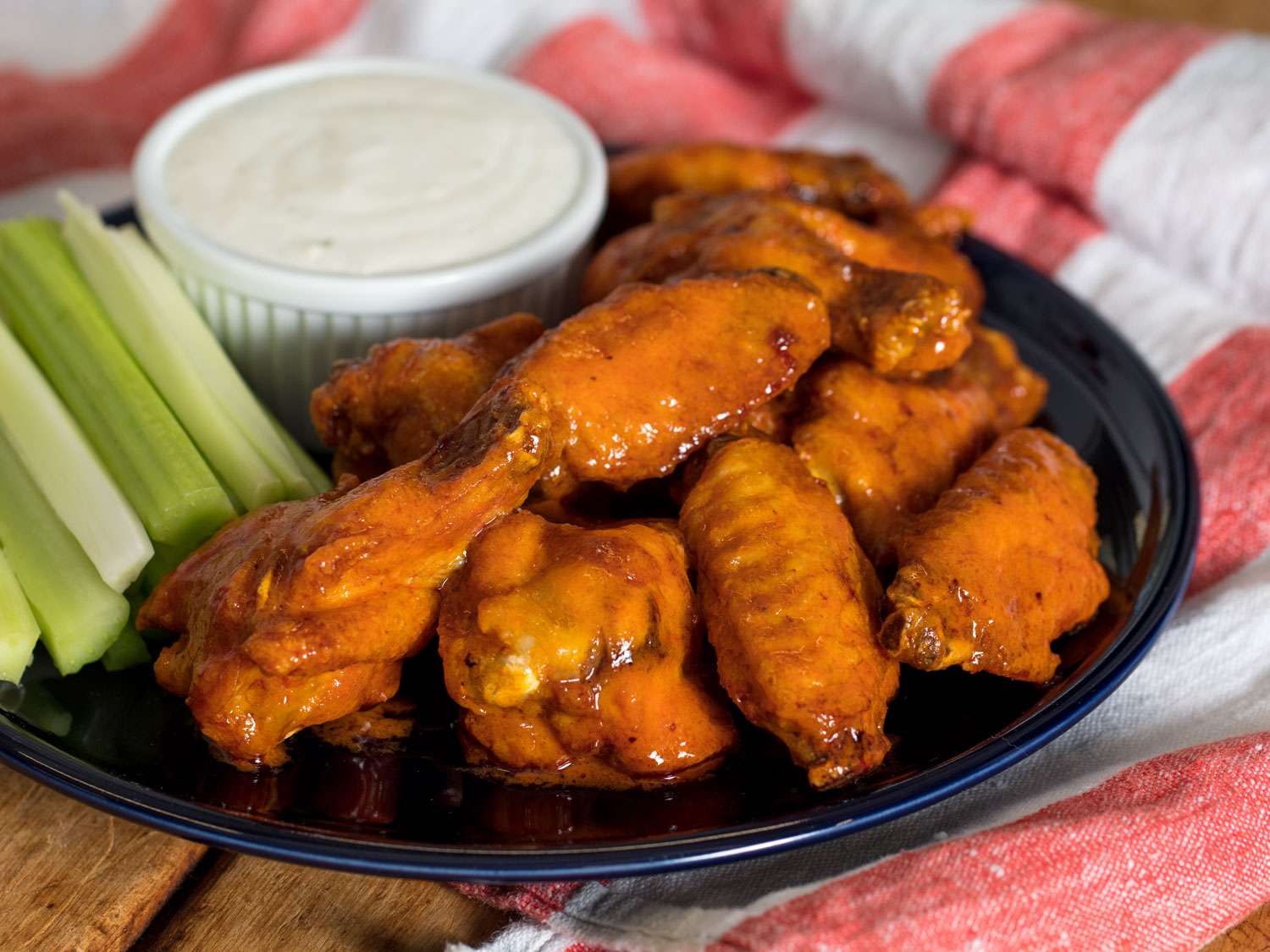 Sous vide Buffalo wings on a blue plate with bowl of blue cheese dressing and celery on the side.