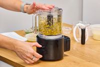 A person chops vegetables in the KitchenAid Go Cordless 5-Cup Food Chopper