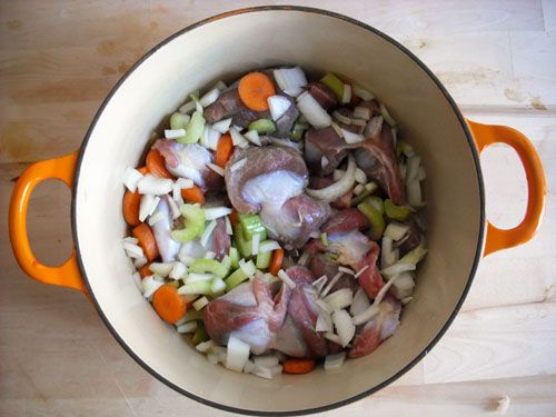 Turkey gizzards in a Dutch oven with chopped vegetables.