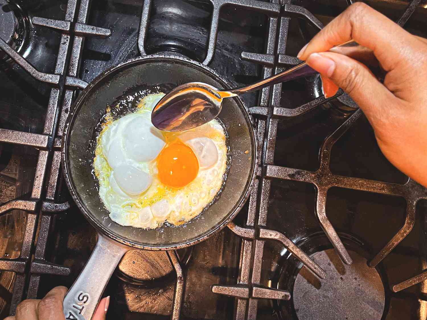 A vibrant egg nearly done frying in a pan.