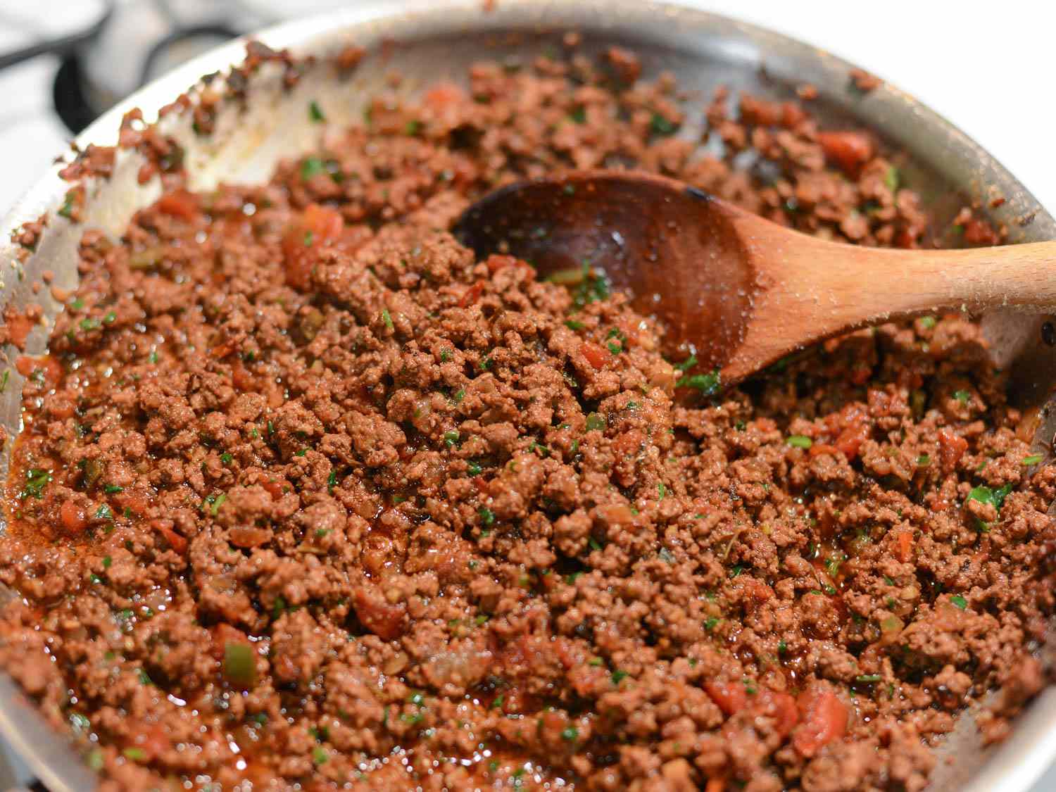 Stirring a spiced beef mixture in a pan for San Antonio-style tacos.