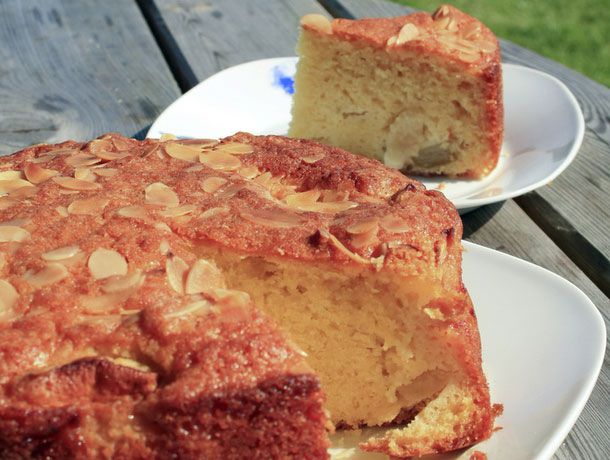 A Dorset apple cake with a slice cut out on a plate behind the cake. 