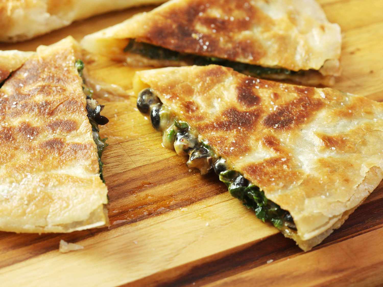 Slices of a homemade vegetarian spinach, black bean, and chipotle quesadilla. 