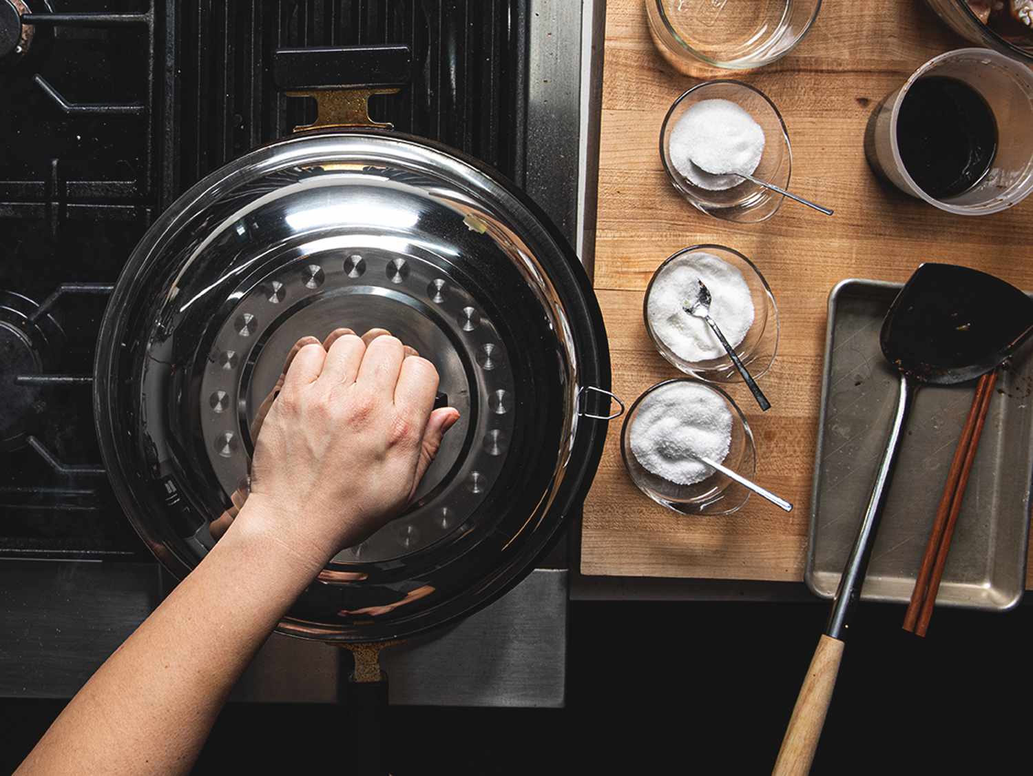 A hand placing a lid on a wok.
