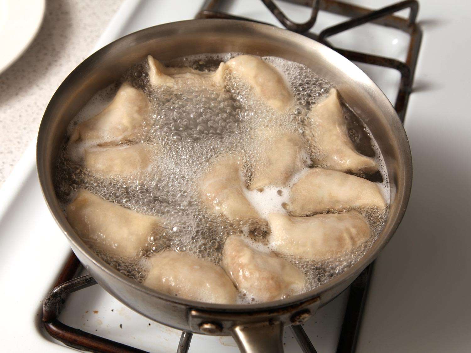 A pan of dumplings being boiled, demonstrating heat through convection.