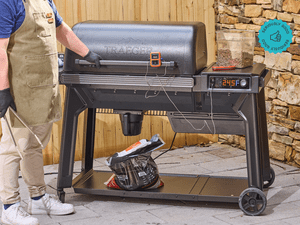 A person standing in front of the Traeger Woodridge pellet grill on a patio