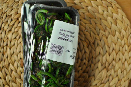 Two shrink-wrapped styrofoam trays of fiddlehead ferns from a produce market.