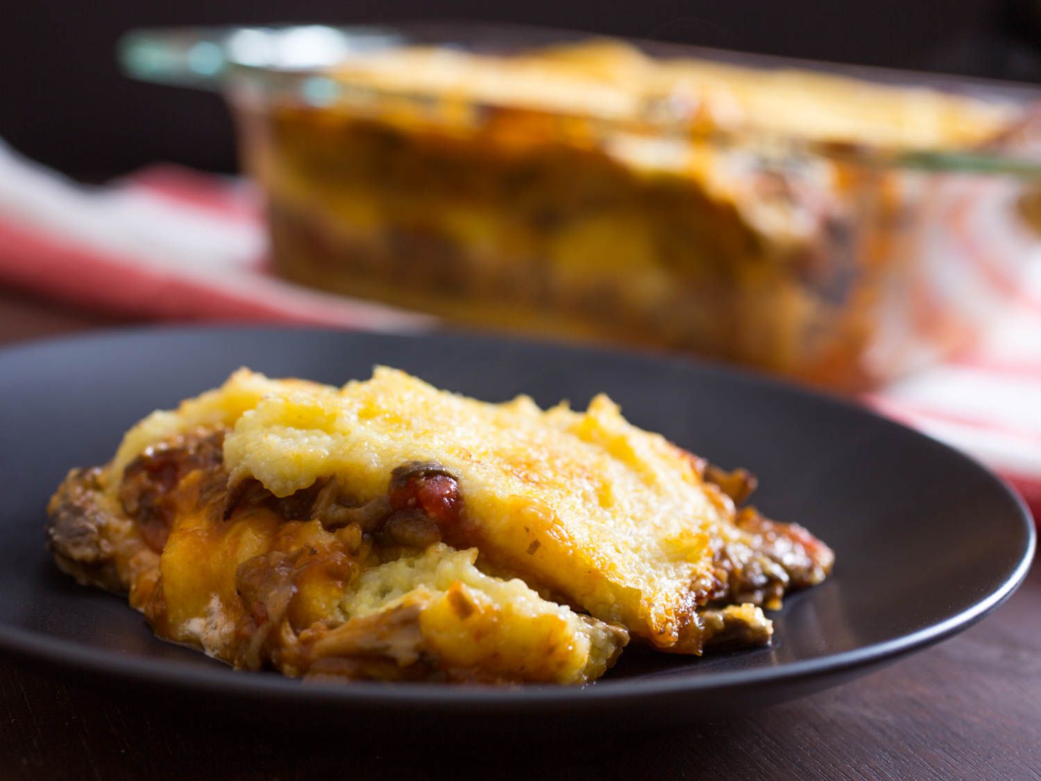 A heap of polenta lasagna on a serving plate, waiting to get drizzled with Parmesan cream.