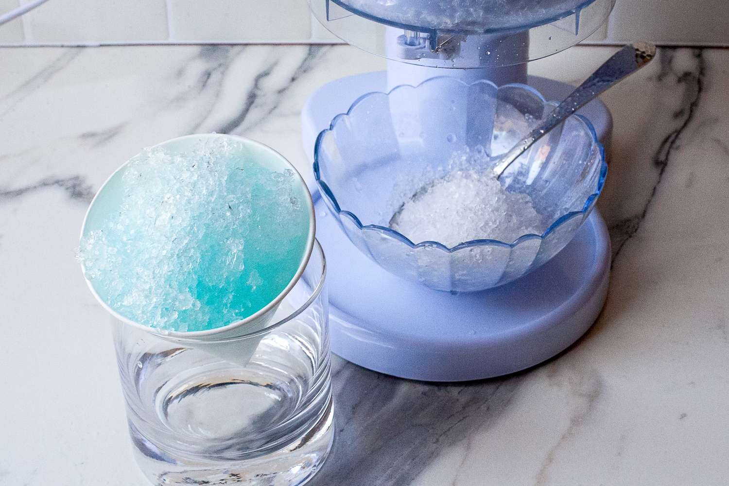 Snow cone being prepared with a machine on a counter