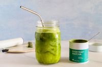 A glass of Rishi Tea Everyday Matcha next to the container