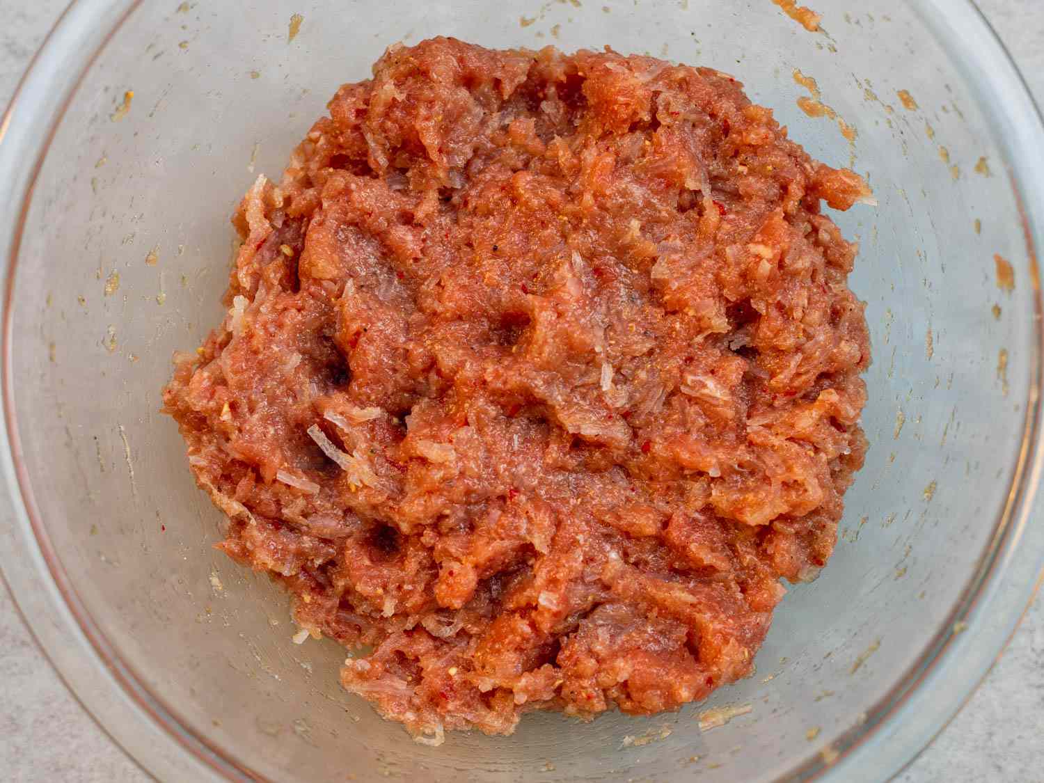 Overhead view of a bowl containing ground pork mixed with seasoning for nem chua.