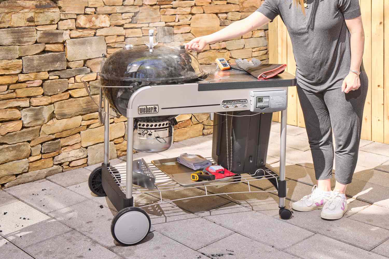 A person standing by the Weber Performer Deluxe Charcoal Grill 22