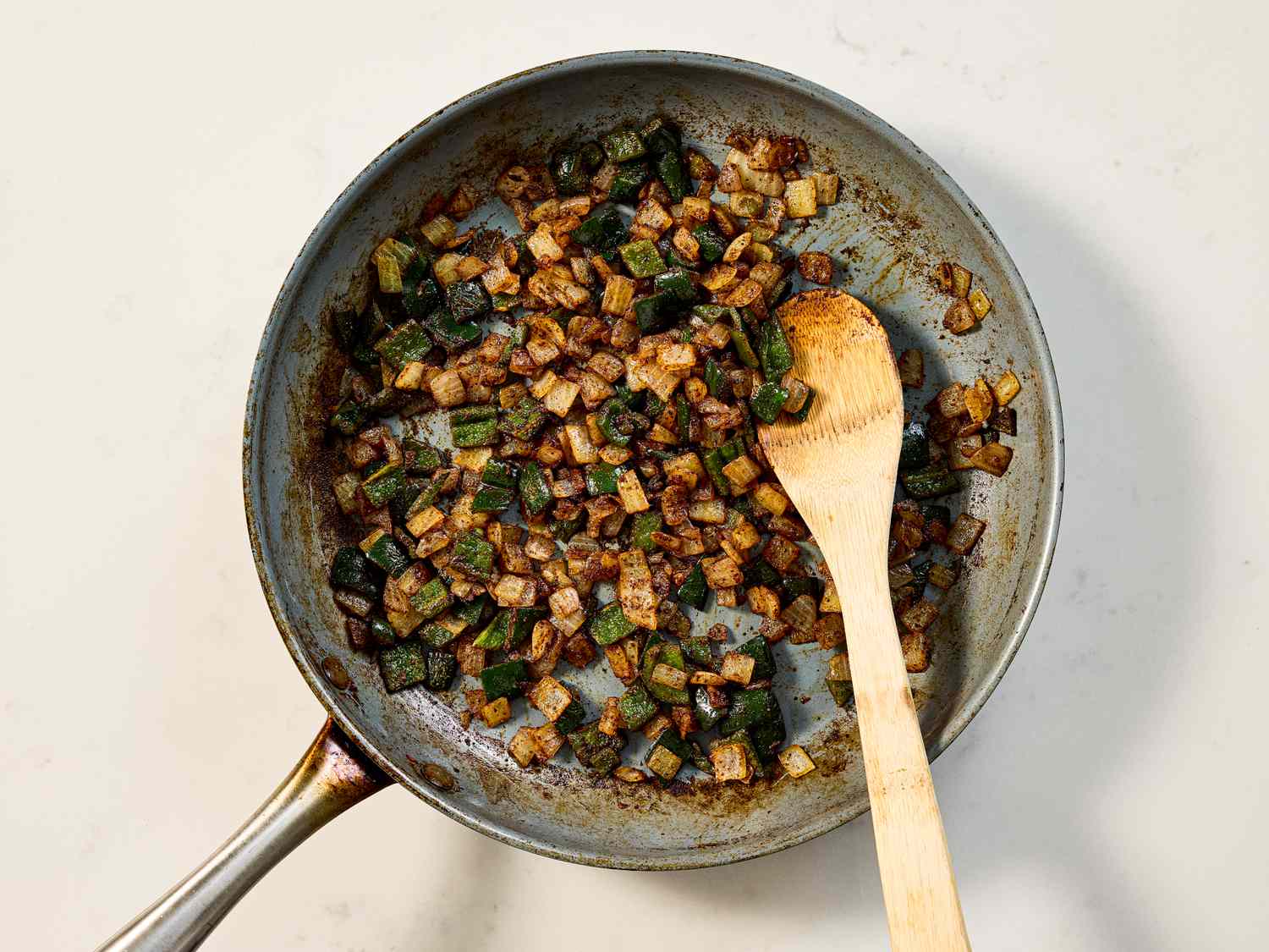 Cooking diced vegetables in a skillet with a wooden spoon