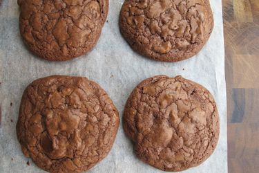 Overhead view of a chocolate chip brownie cookies, arranged on a sheet of parchment paper.