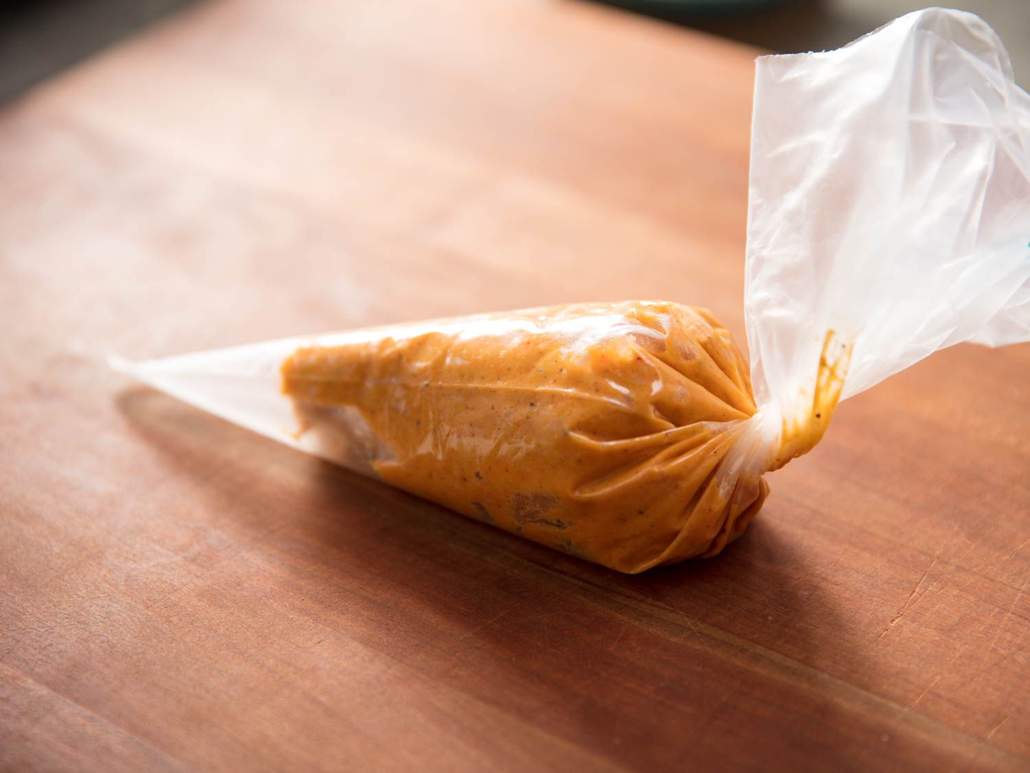 A plastic piping bag holding the sev dough on a wooden cutting board.