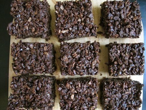 Nine chocolate rice crispie treats arranged in a grid on a surface