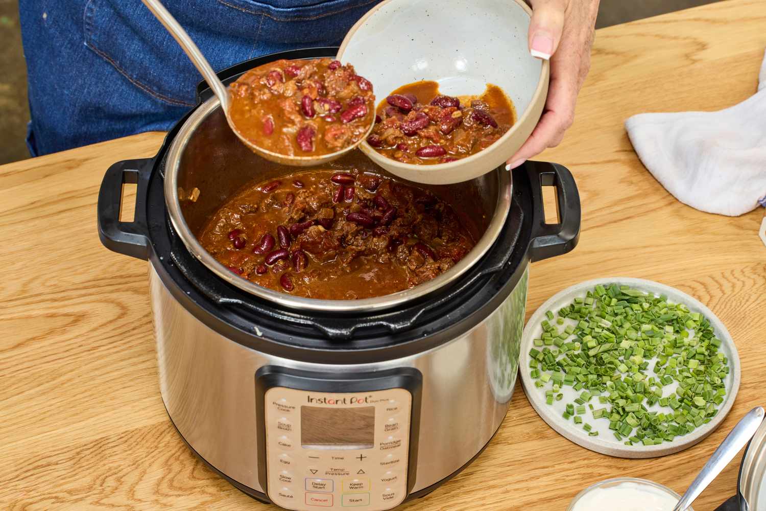 A person scoops chili from the Instant Pot Duo Plus 6-Quart 9-in-1 Pressure Cooker