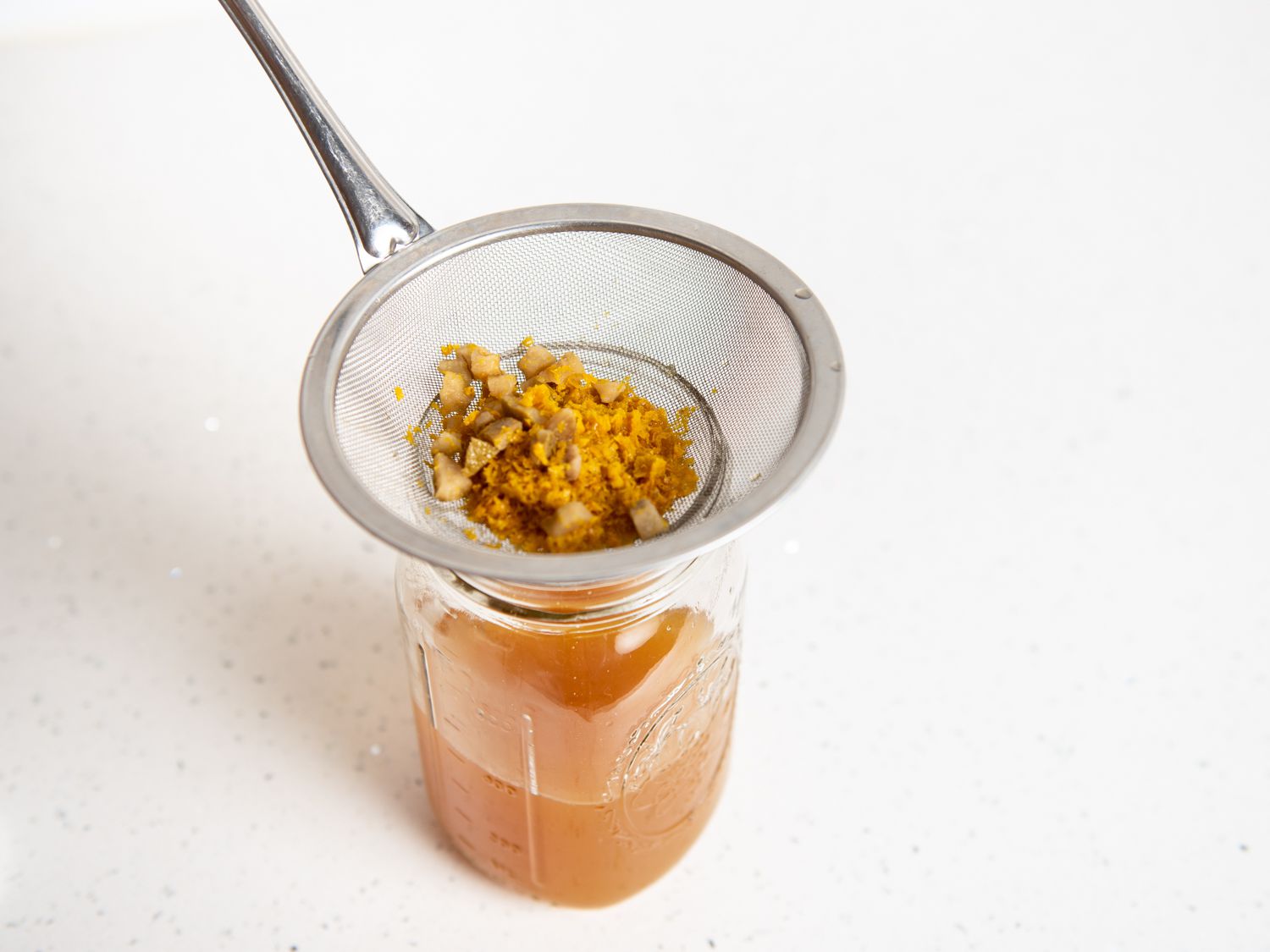 straining DIY orange liqueur into a jar