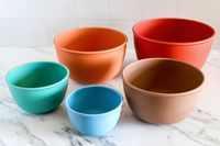 Five Bamboozle mixing bowls of varying sizes and colors arranged on a marble surface