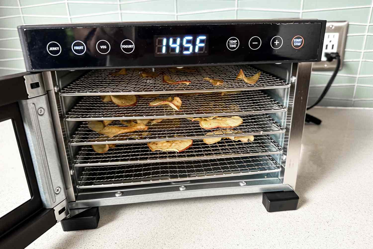 The Cosori food dehydrator with apple chips drying on its racks