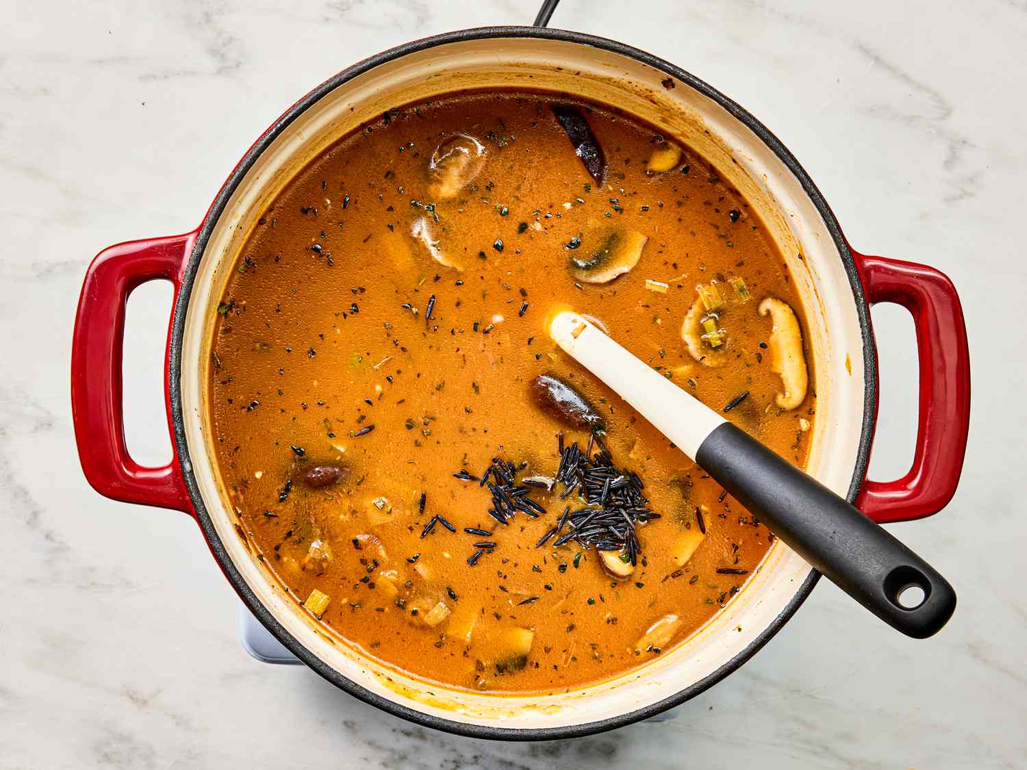 Pot of soup with mushrooms and a spoon inside
