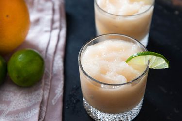 Frozen Mezcal Paloma cocktails served in two rocks glasses, garnished with thin half slices of lime