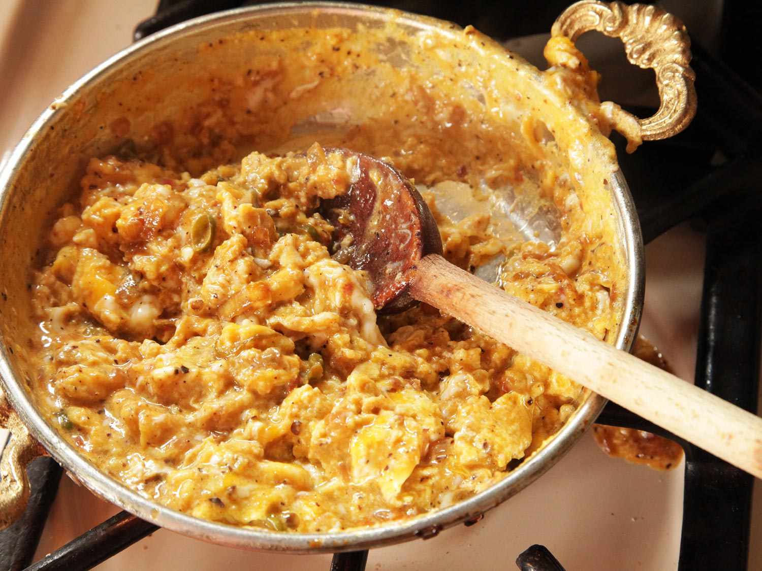 Gently stirring reserved vegetables into soft-cooked eggs 