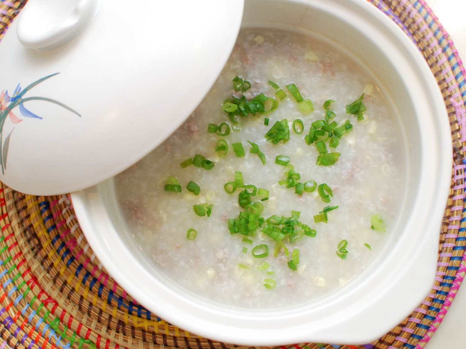A finished pot of pork and sweet corn congee, garnished with sliced scallions.