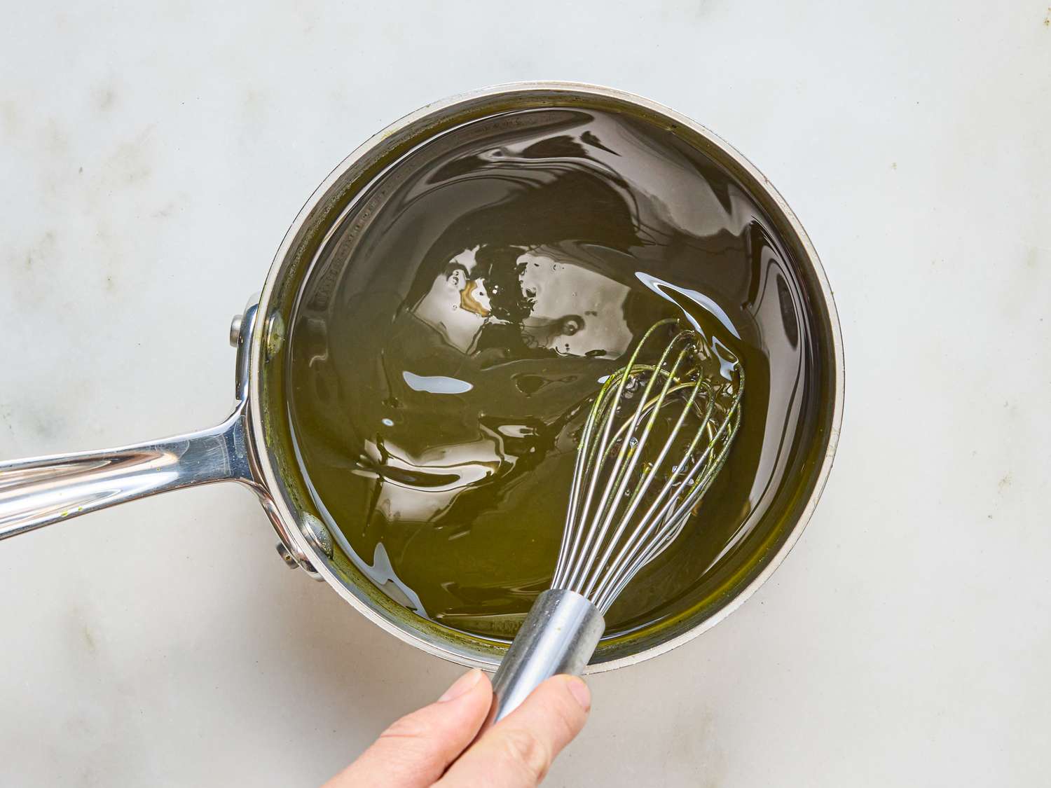 A pot with matcha mixture being stirred with a whisk