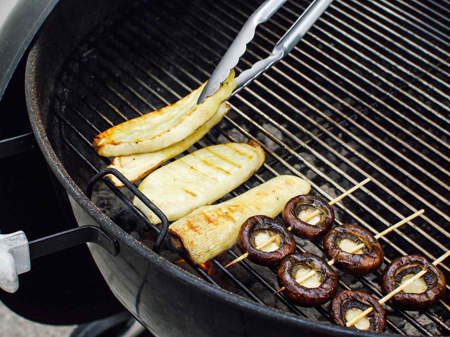 Flipping king trumpet mushrooms and skewered cremini caps on the grill.